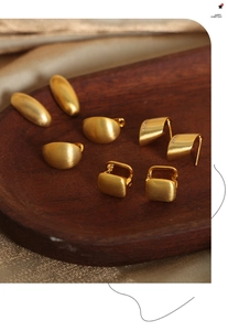 Detailed view of matte brushed gold geometric earrings set on a dark wooden tray
