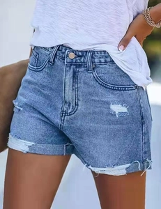 Détail de la texture denim et de l'ourlet déchiré sur un short en jean bleu