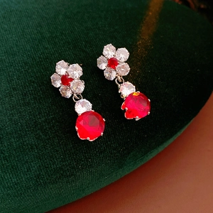 Detailed view of luxury drop earrings with white flower tops and round red zircon crystals