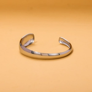 Macro detail of polished silver stainless steel open bangle with smooth retro lines
