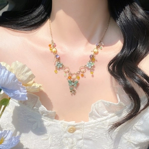 Detail of floral butterfly necklace with pastel beads on model collarbone