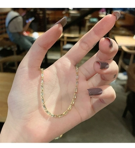 Detail of gold-plated chain necklace with rectangular zircon stones held in hand