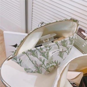 Detail of floral canvas makeup bag with green thistle prints and metal zipper closure