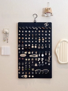 Wall-mounted black felt jewelry organizer featuring multiple slots for earrings and sunglasses