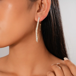 Macro view of geometric gold-toned stud earring with sparkling rhinestone accents on ear