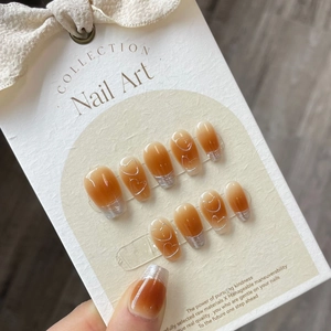 Close-up of caramel gradient press-on nails with silver French tips and heart patterns