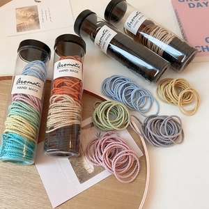 Elastic hair ties set in 4 transparent jars on a wooden tray with aesthetic background