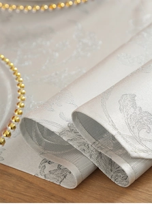 Close-up of light gray jacquard table runner with delicate floral leaf patterns