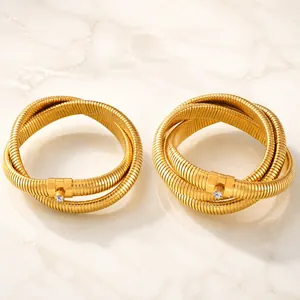 Dettaglio dei bracciali in acciaio al titanio placcato oro con trama a spirale e zirconi