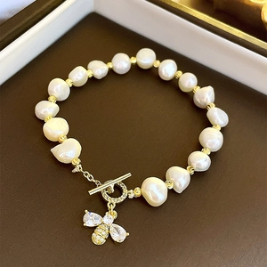 Detailed view of pearl bracelet featuring a crystal bee pendant and golden toggle clasp