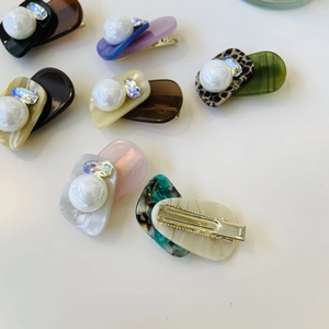 Detailed view of acetate duckbill hair clips with pearls and crystals in various colors