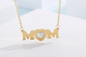 Macro shot of MOM necklace pendant with white heart-shaped opal in golden finish