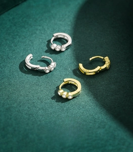 Close-up of S925 sterling silver huggie earrings with cubic zirconia in gold and silver