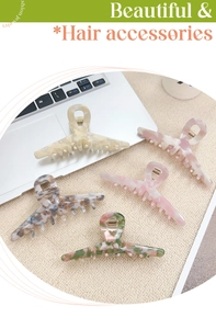 Detailed top view of five large acetate hair claws in pastel marble patterns on a textured mat