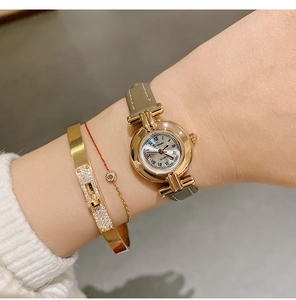 Close-up of elegant DINIMI women's quartz watch with Roman numeral dial and leather strap