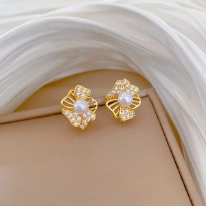 Detailed view of gold flower earrings with white pearls and diamonds on silk