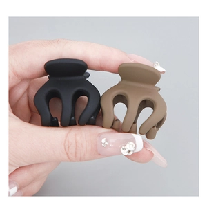 Macro shot of matte black and brown pumpkin claw clips held in hand for hairstyling