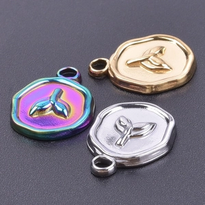 Macro shot of polished stainless steel fishtail charms in gold, silver and rainbow finish