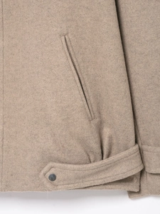 Detail view of khaki wool jacket pocket and adjustable hem with metallic button