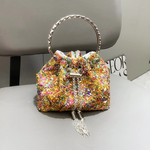 Colorful rhinestone bucket handbag with gold beads and silver metal handles on leather chair