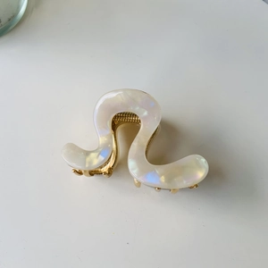 Pearlescent white wavy hair claw clip with gold metal hinge shown from a top view