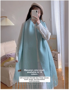 Detail of light blue long knit scarf with tassels shown in a cozy home setting
