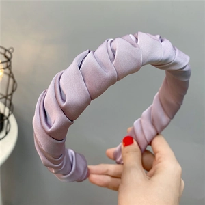 Detail of purple pleated satin headband with a twisted knot design and silky finish