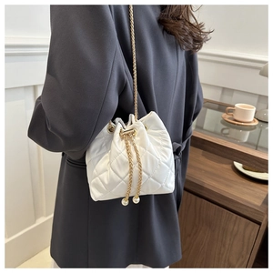 Detail of white quilted bucket bag with gold chain strap and elegant pearl drawstring