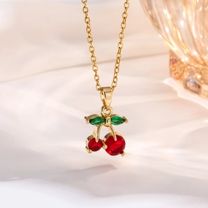 Macro detail of a cherry pendant necklace with red and green crystals on white silk