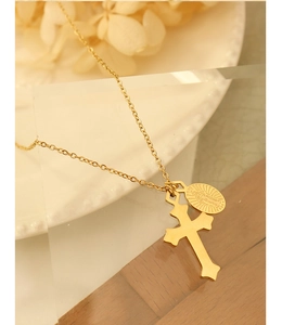 Détail du pendentif croix dorée et du médaillon ovale religieux sur chaîne fine