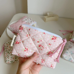 Macro detail of quilted cotton pouch with pink floral pattern and simple wish label