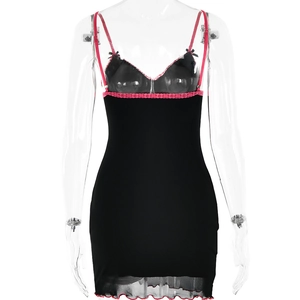 Detail of black mini dress with pink lace trim, bow decoration, and scalloped hemline