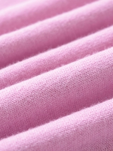 Macro shot of soft pink knit fabric texture with fine fiber detail on this women's sweater