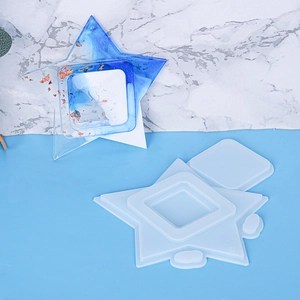 Macro detail of star and square silicone molds with blue resin casting on marble background