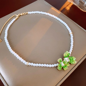 Detailed shot of pearl necklace with green faceted bow pendant and gold plating finish