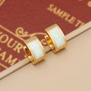 Detailed macro view of gold-plated hoop earrings featuring light green enamel inlay