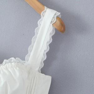 Detail of white lace strap with intricate embroidery on pleated French style top
