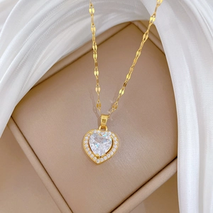 Close-up of heart necklace in gold with pave crystals on beige jewelry box with silk