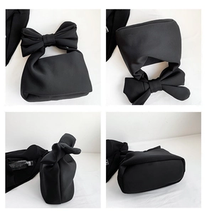Detail view of black nylon shoulder bag featuring puffy bow handle and quilted texture