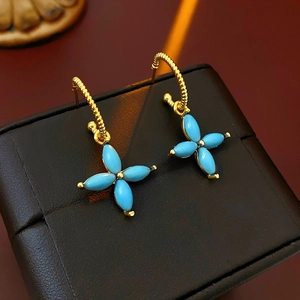 Detail of gold-plated clover earrings with turquoise petals on a leather jewelry box