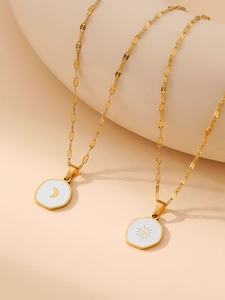 Macro shot of gold sun and moon enamel pendants on a unique wave-shaped flat chain