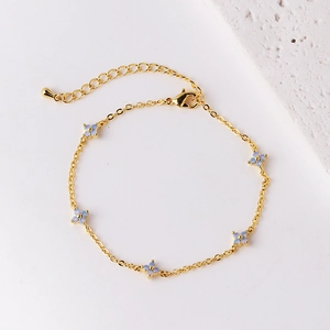 Elegant gold chain bracelet with five light blue opal flower charms on white background