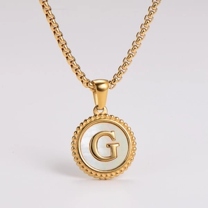 Detailed close-up of a gold stainless steel round necklace featuring a white shell letter G