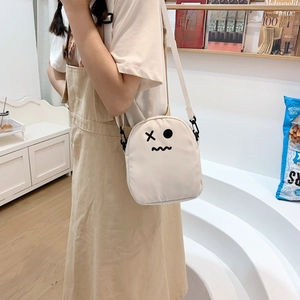 Détail du sac bandoulière en toile blanche avec visage de dessin animé rigolo