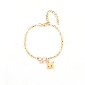 Elegant gold bow bracelet with sparkling rhinestones and M letter pendant on white background