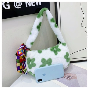 Detail of plush faux fur handbag with green flowers and silk scarf next to phone for scale