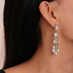 Close-up of sparkling silver tassel earrings with geometric crystals worn by a model
