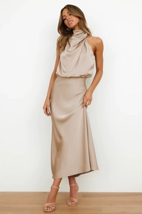 Detail of elegant champagne satin halter maxi dress with flowing fabric texture