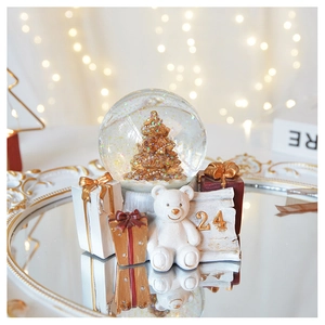 Detail of Christmas snow globe with white bear and golden tree on mirrored tray