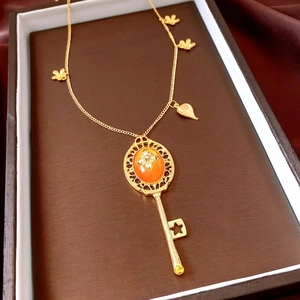 Macro shot of vintage gold key necklace with orange gemstone and floral details